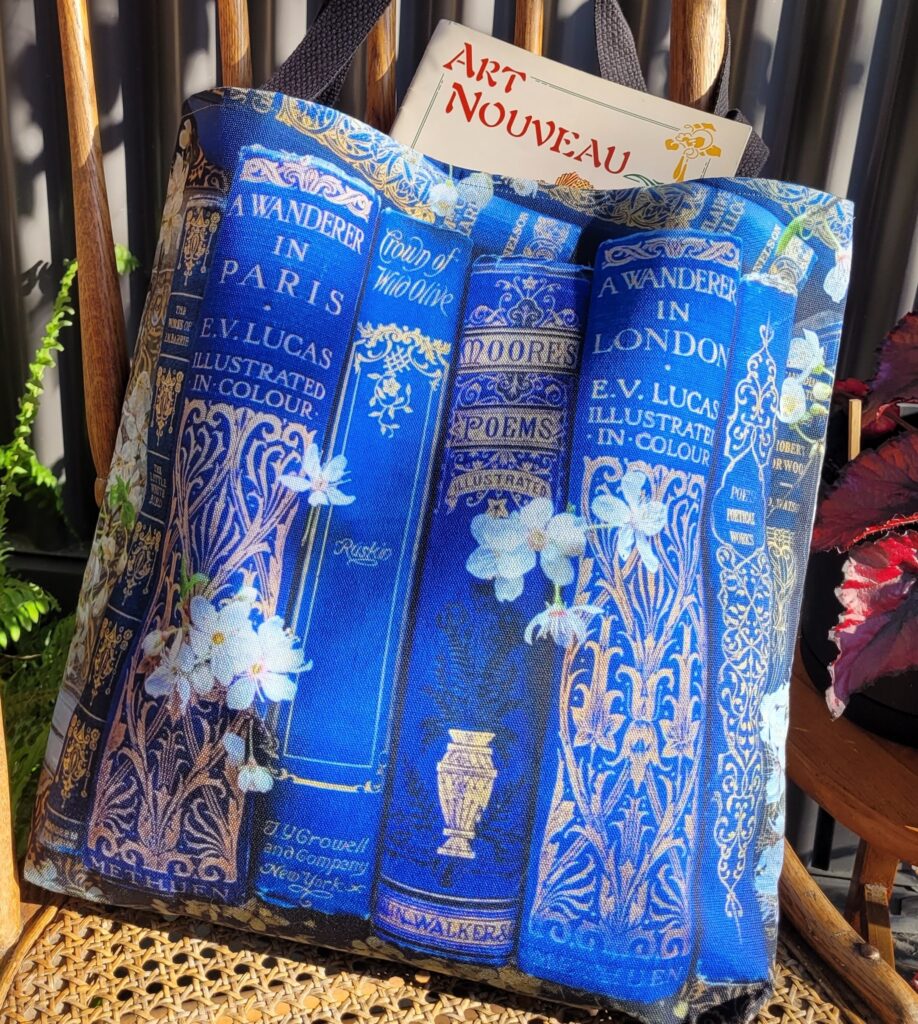 Blue Book Tote gift for bibliophiles with art nouveau bookspines and white spring blossoms.